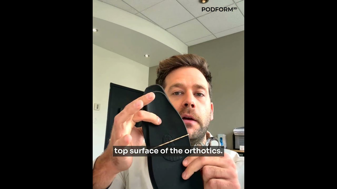 Dr. Antonin Bérubé holding a black 3D-printed foot orthotic shell during the top-cover demonstration